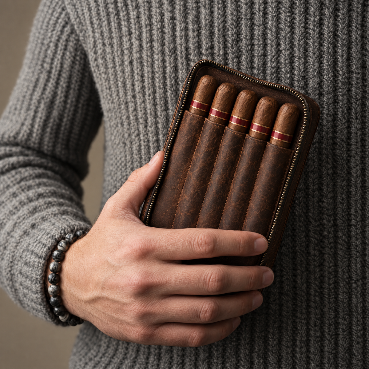 Man in a grey knit sweater holding the open leather organiser with five cigars in its pocket
