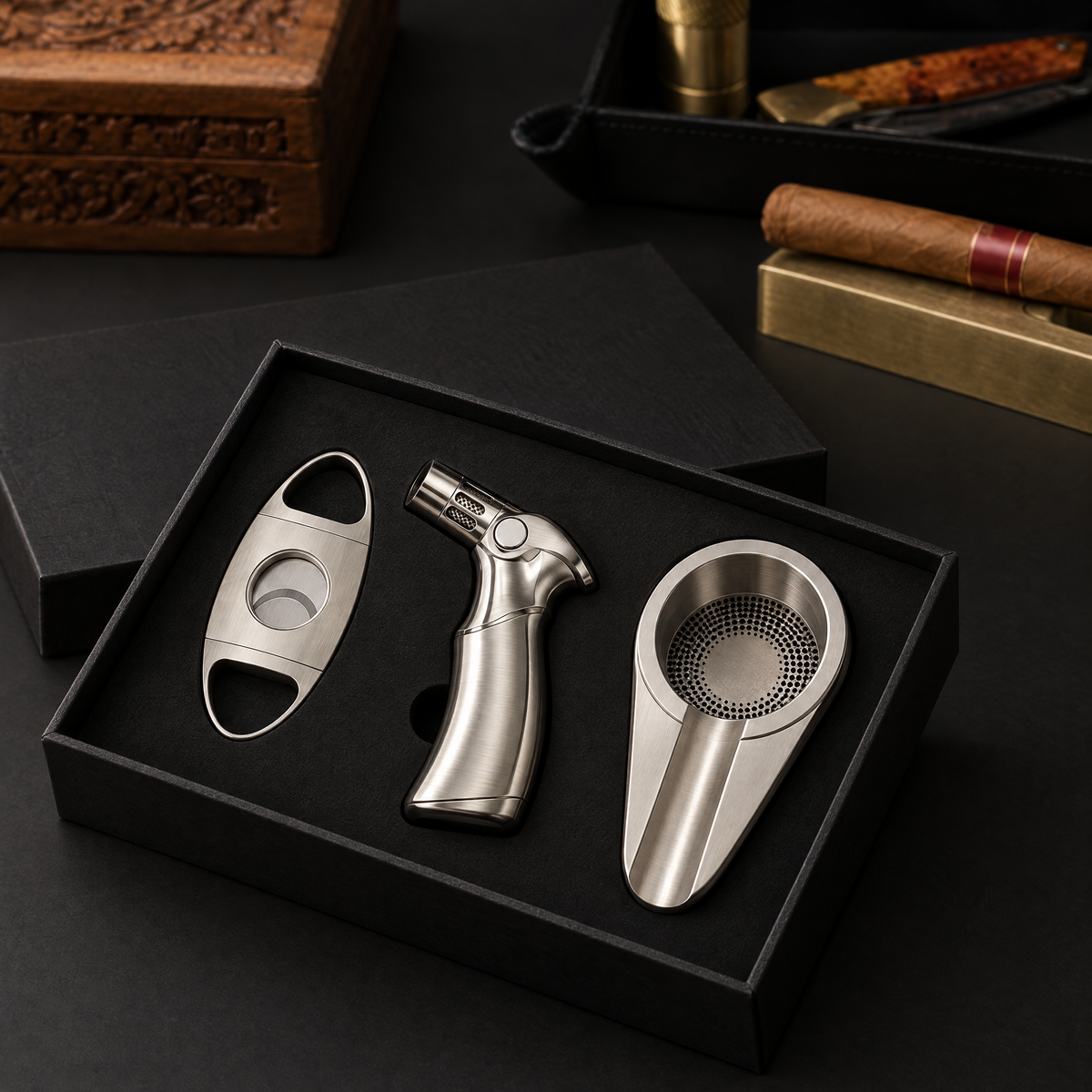 Three-piece cigar gift set in its open black presentation box: guillotine cutter, torch lighter and ashtray