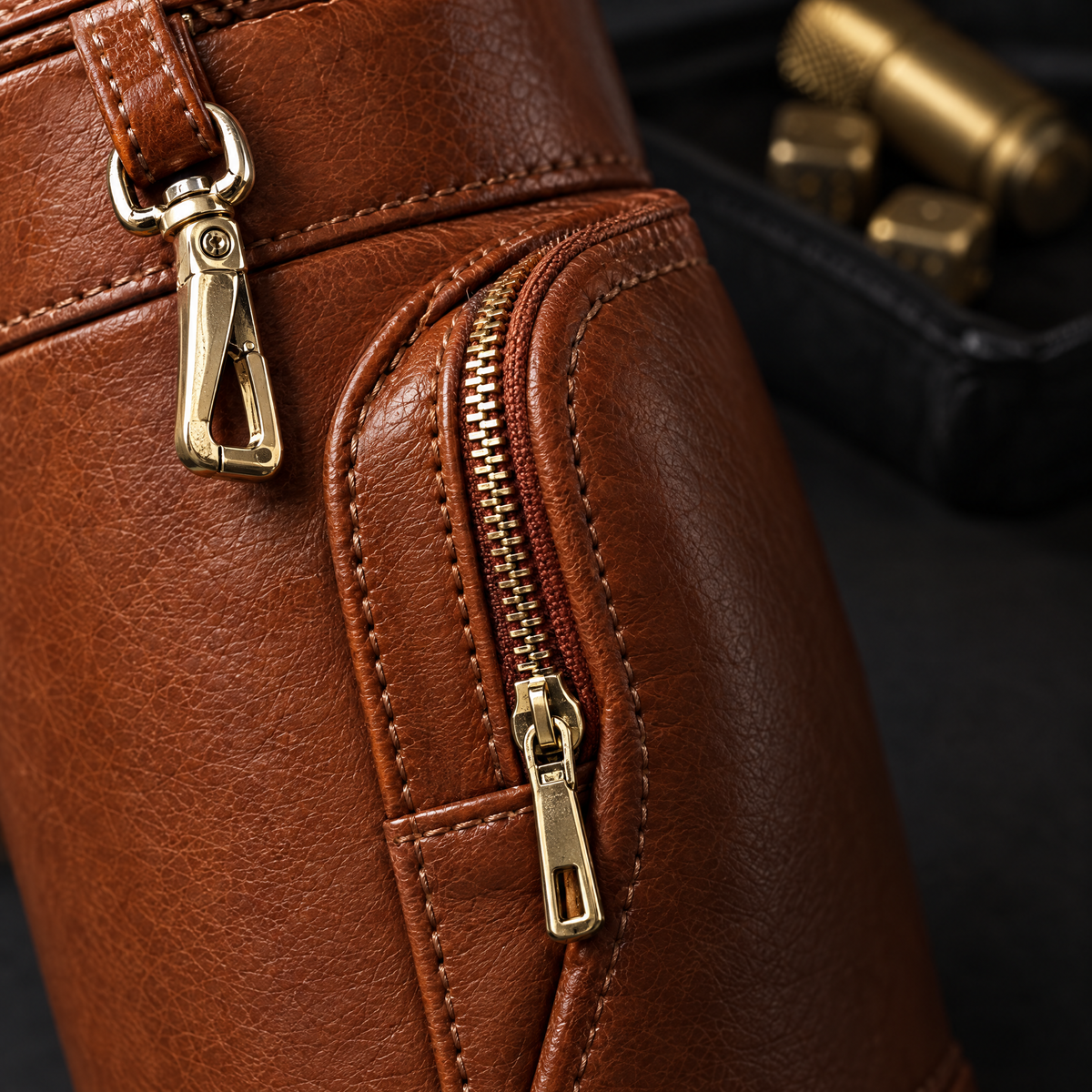 Close-up of the zipped front pocket, the double stitching and the gold swivel clip on its leather strap